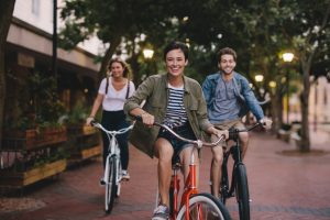 tre leende personer som cyklar